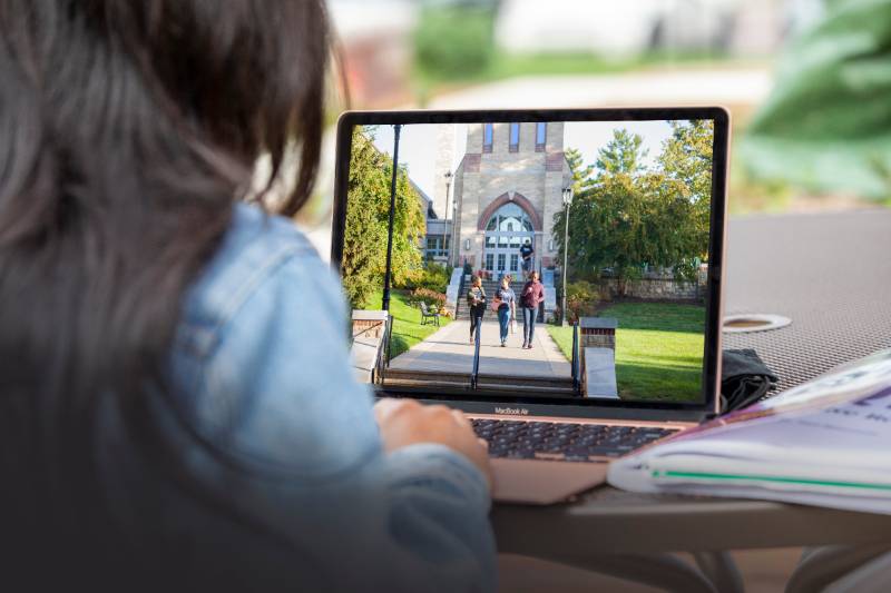 Bryn Athyn College student on laptop looking at image of Bryn Athyn College campus