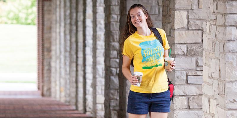 a student smiling after picking up her morning coffee at the College cafe