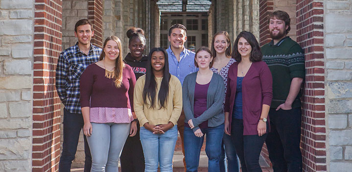 A group of students stand in the colonade