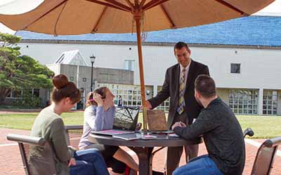 Bryn Athyn College professor speaking with students at an outdoor patio table