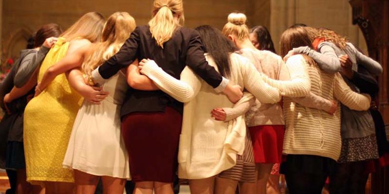 Bryn Athyn College female students stand in a circle with linked arms