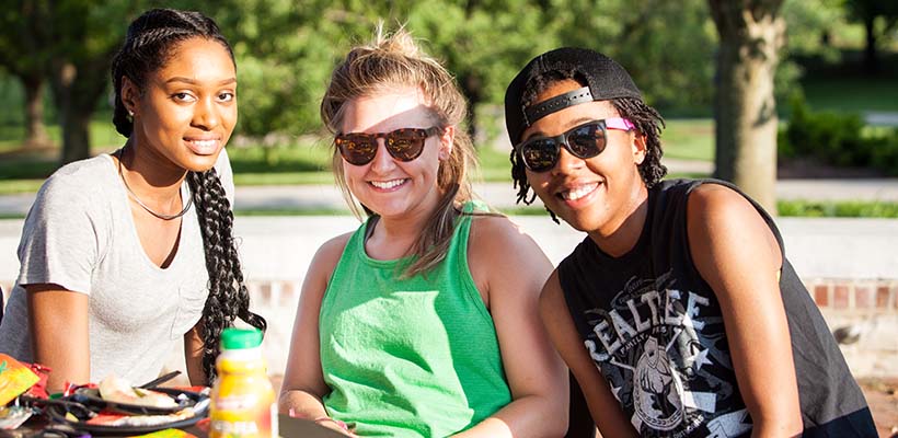 Bryn Athyn College group of three girls sitting on the terrace and smiling at the camera