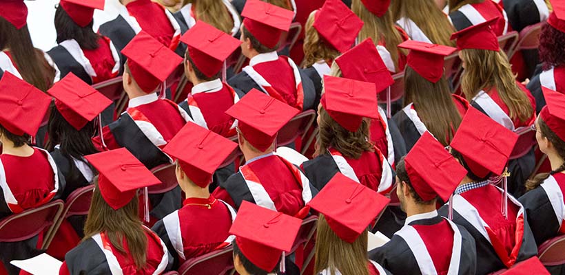 An aerial view of graduates sitting in their caps and gowns.