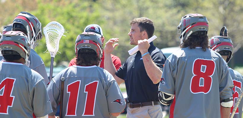 Bryn Athyn College Head Coach Tucker Durkin talking to his lacrosse players in a huddle