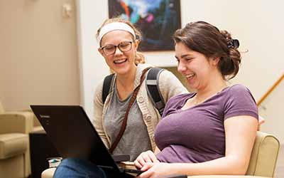 Bryn Athyn College students looking at laptop smiling