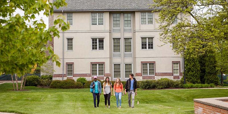 Bryn Athyn College students walking across the green outside of the residence suites