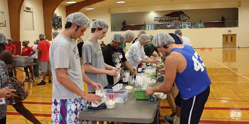 Students participating in a service event, packing boxes of food.